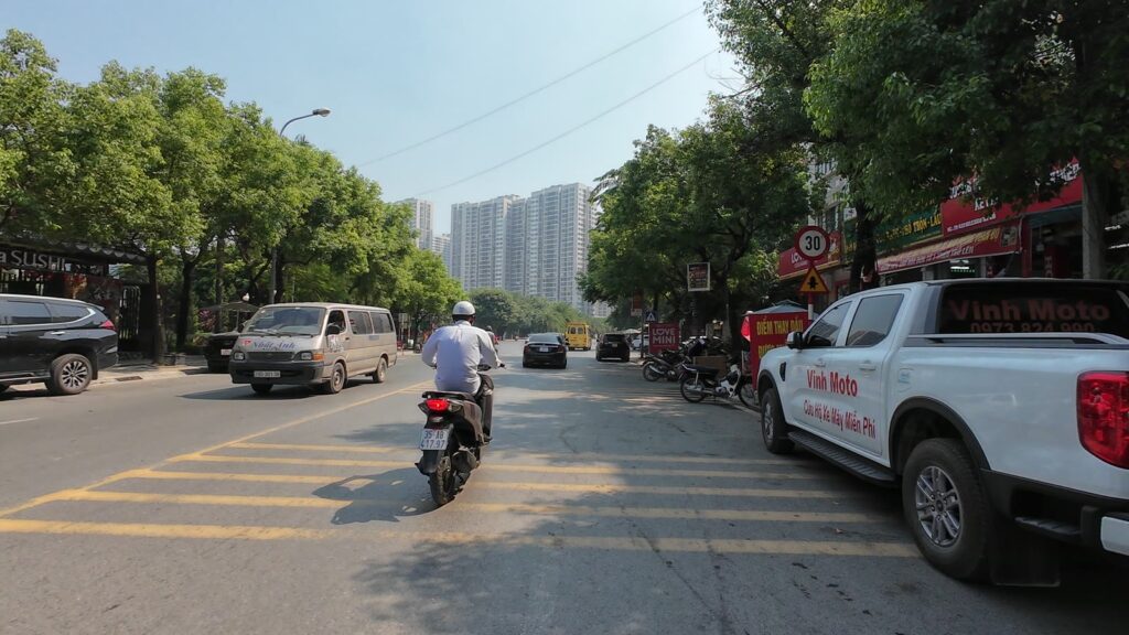 Đường trong Khu A Geleximco An Khánh, hai bên hàng quán mở cửa, phía xa là các tòa chung cư cao tầng