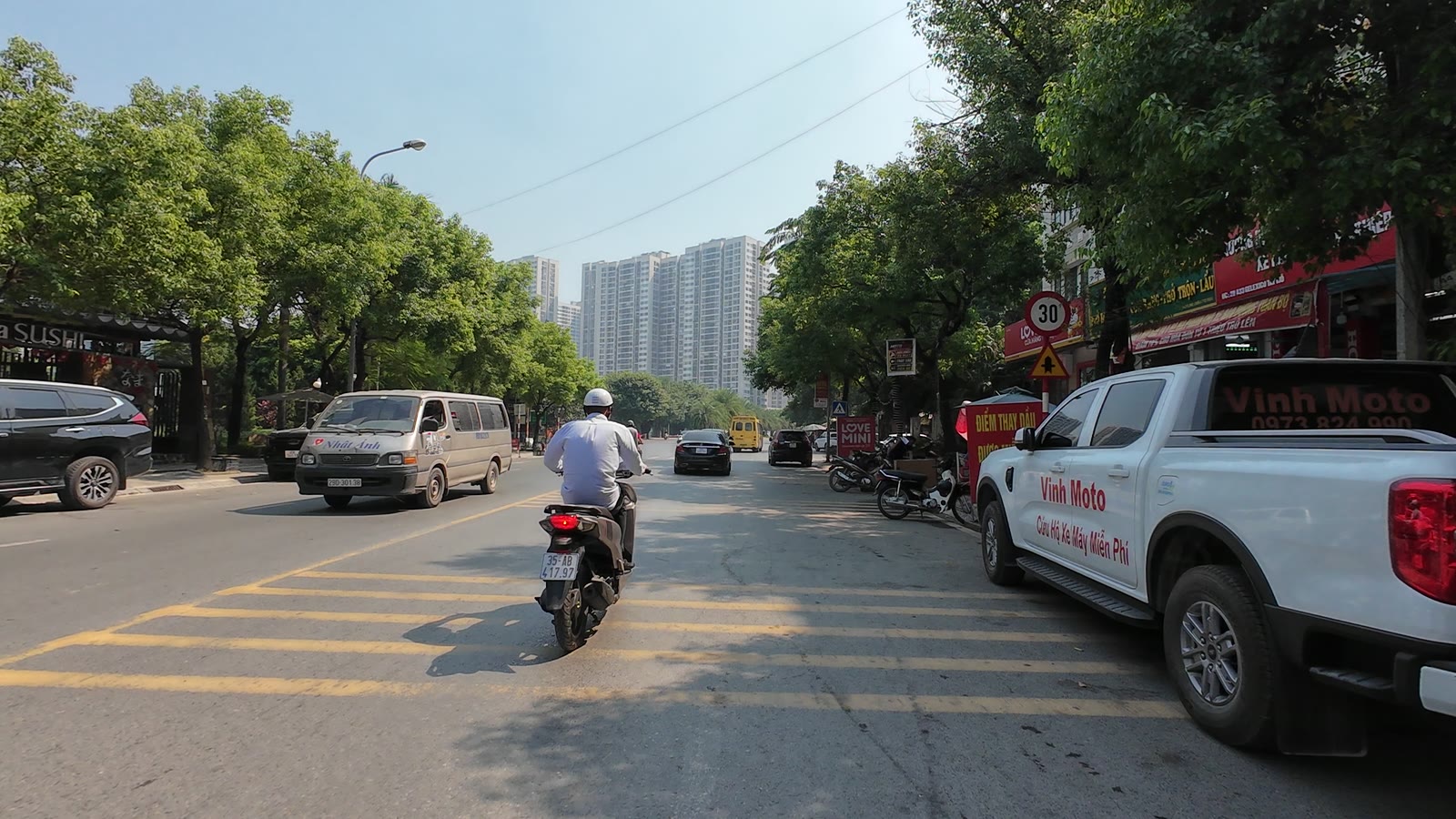 Đường trong Khu A Geleximco An Khánh, hai bên hàng quán mở cửa, phía xa là các tòa chung cư cao tầng