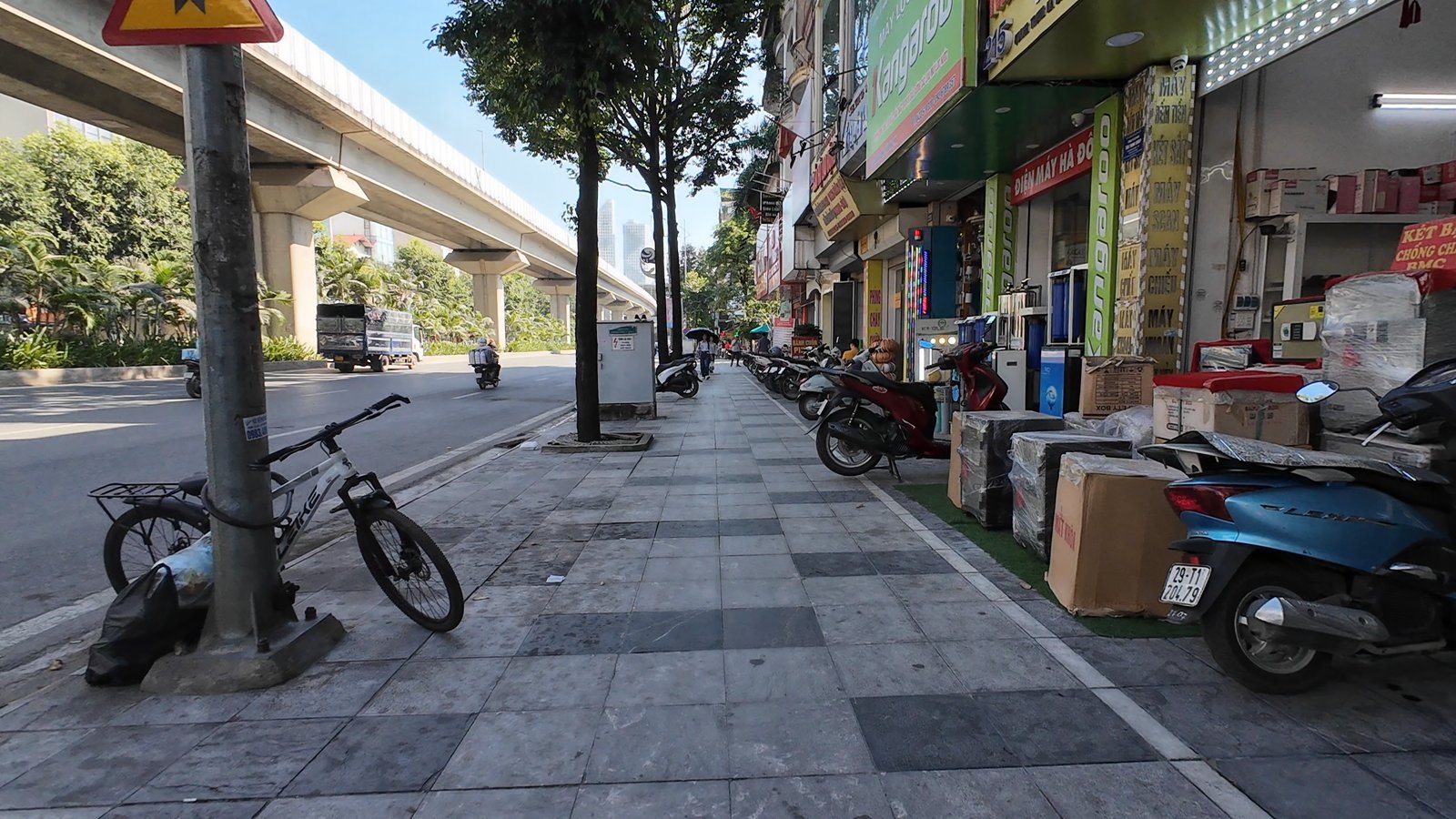 Vỉa hè có bóng cây và hàng quán dọc đường đi bộ từ ga La Khê lên ga Hà Đông